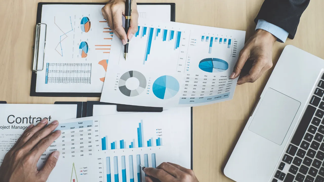 A collection of financial charts on a work table with a laptop