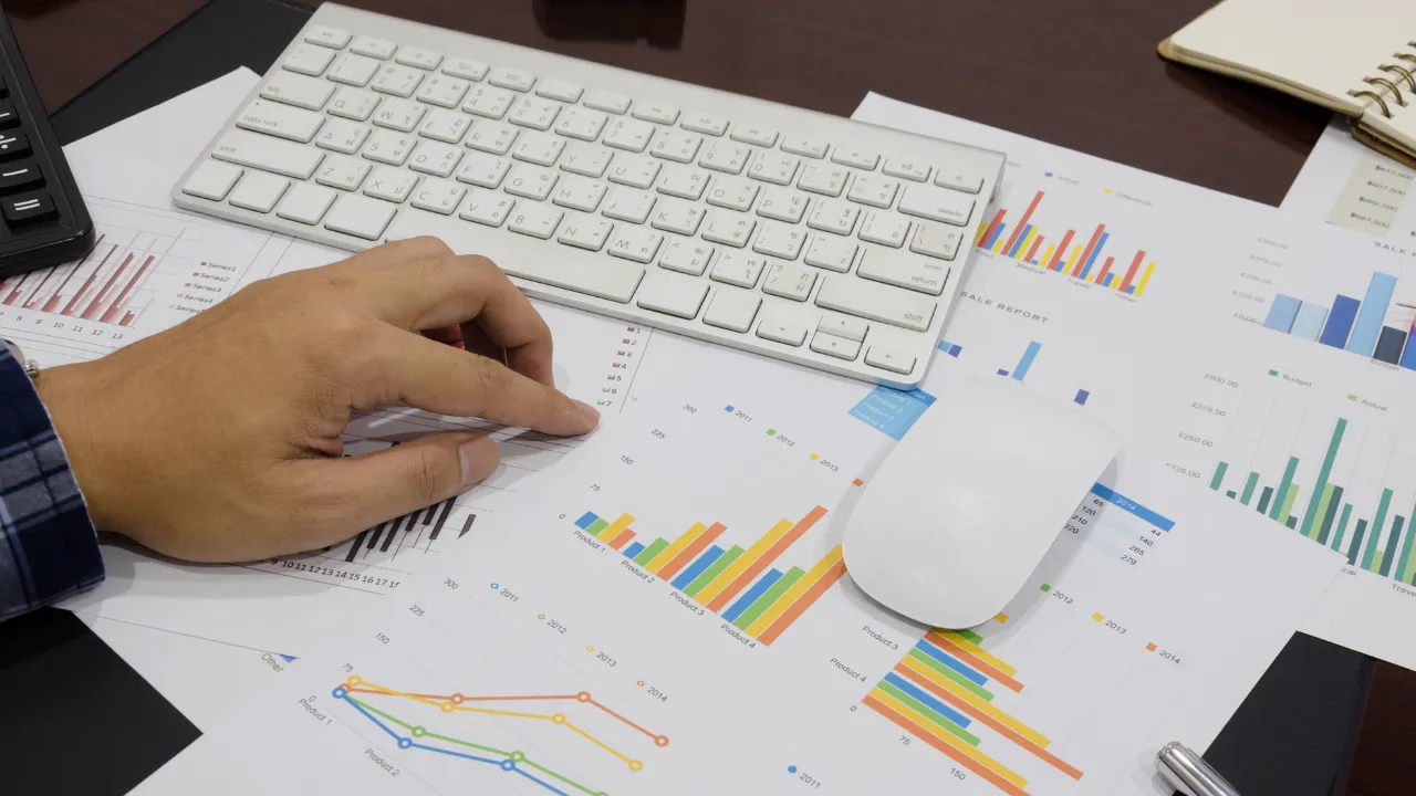 An investor working at his desk on a computer with charts in front of him
