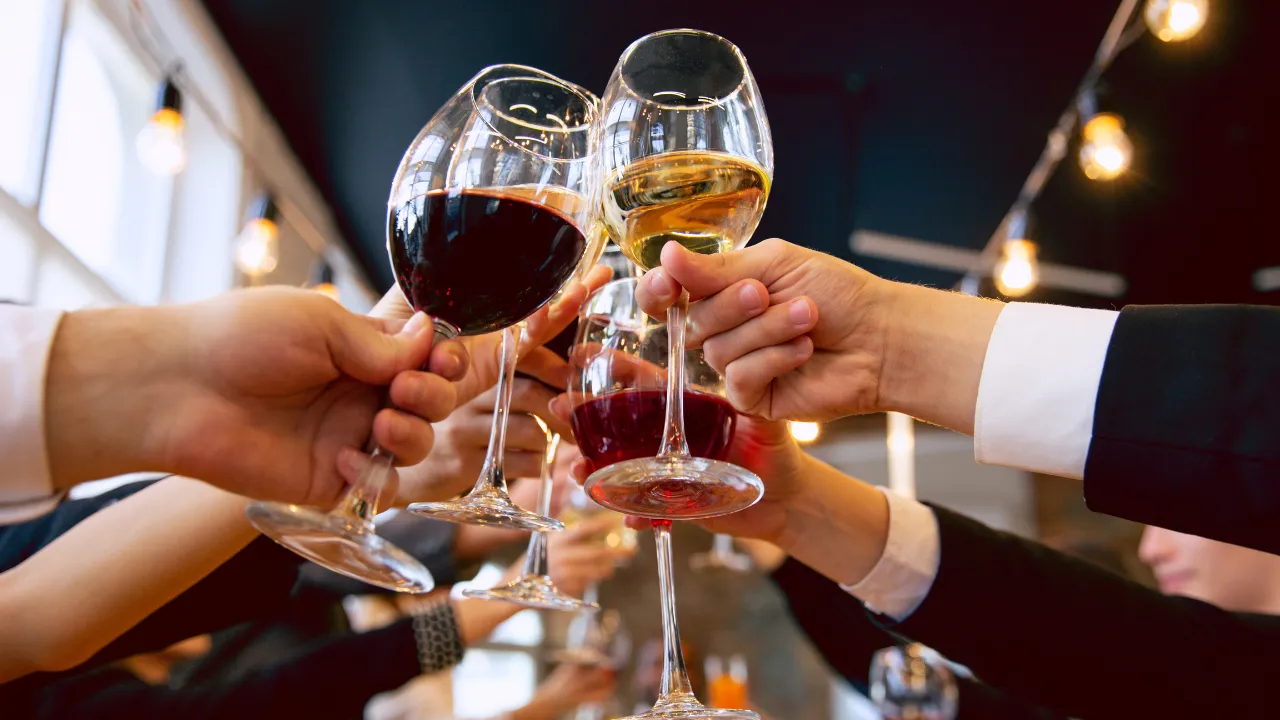 A bunch of people holding wine glasses in the air in cheers