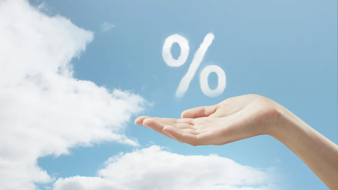 A hand holding a percentage sign in the clouds