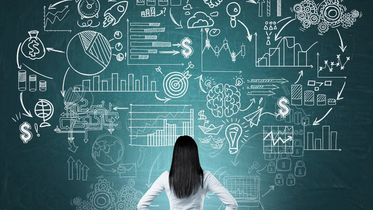 A business woman standing in font of a though board