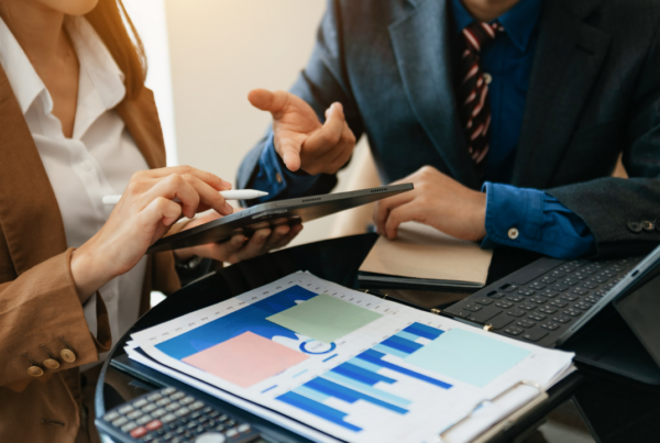 Two business professionals discussing finances over charts | Scott Legal, P.C. Two business professionals discussing finances over charts
