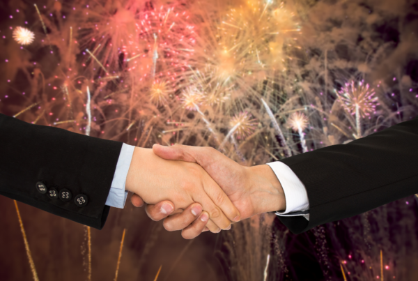two business professionals shaking hands with fireworks in the background | Scott Legal, P.C. two business professionals shaking hands with fireworks in the background