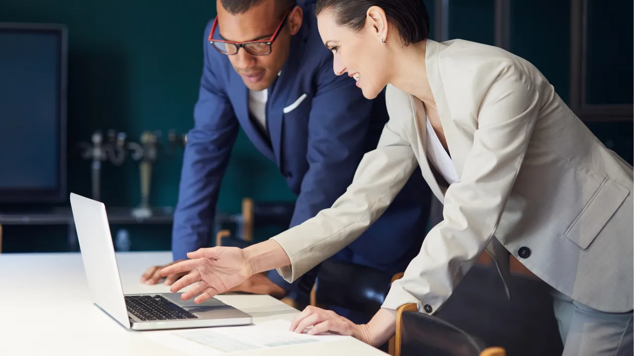 Two corporate individuals considering their options on a laptop