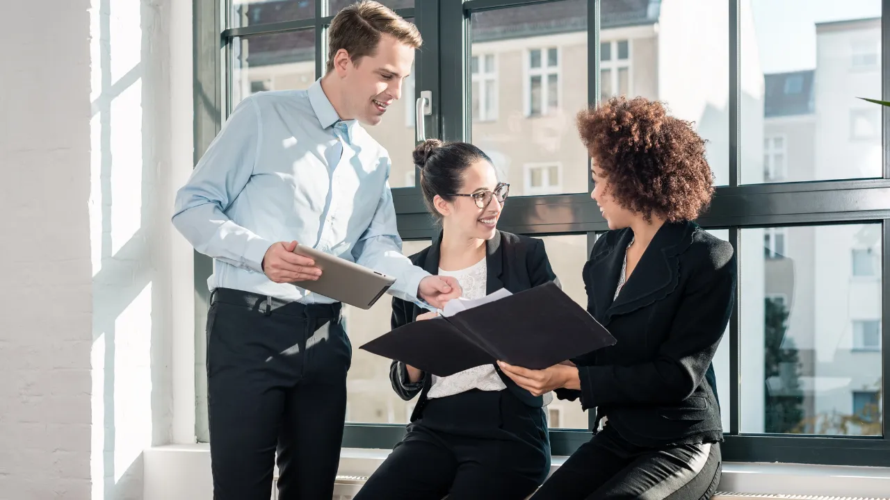 3 employees sitting together looking at notes