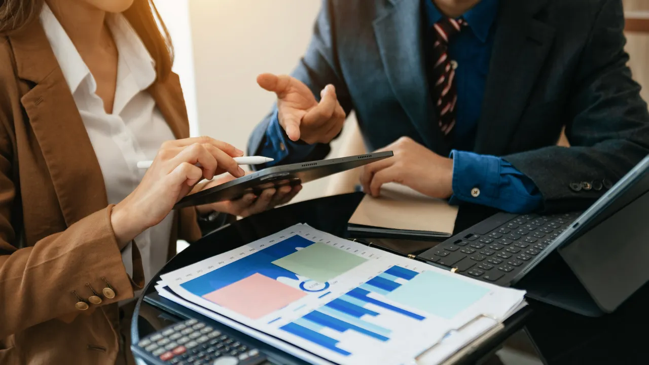 Two business professionals discussing finances over charts