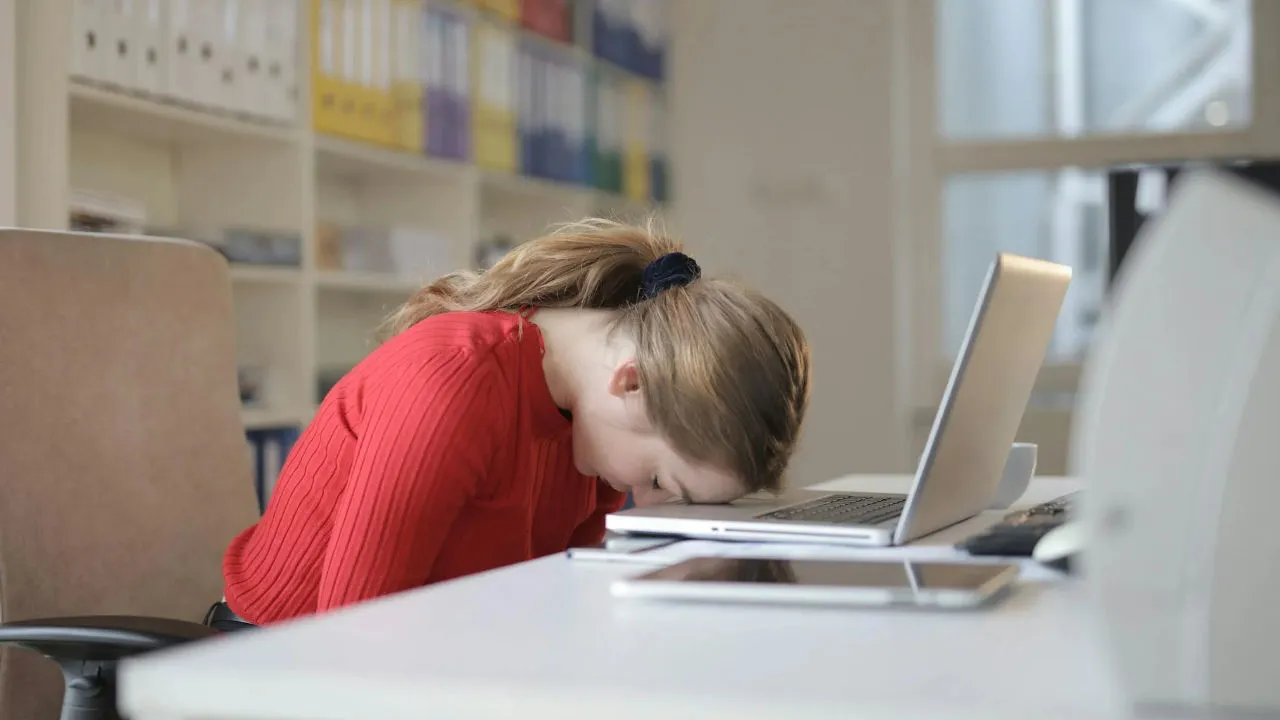An office worker having a nap on the desk.