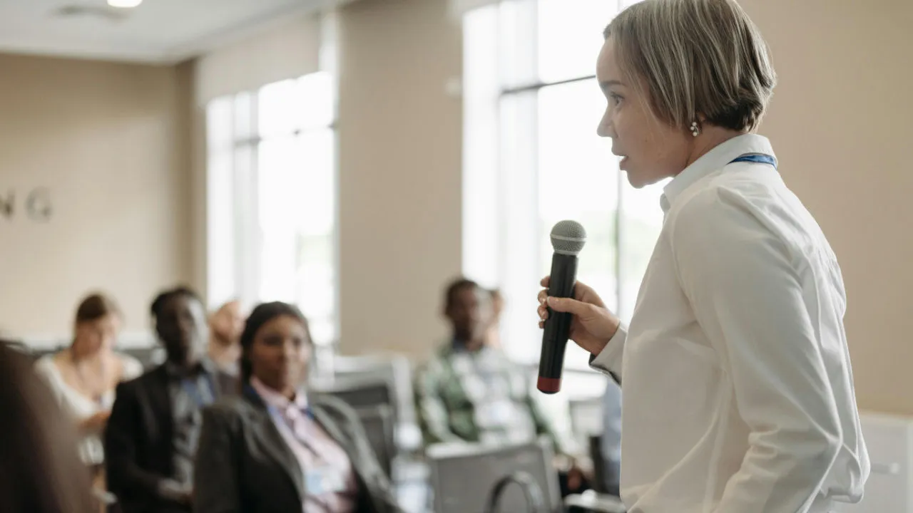 A speaker at a conference in front of a crowd.