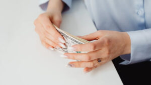 Hands of a woman holding U.S. dollar bills, symbolizing prevailing wage in employment-based immigration