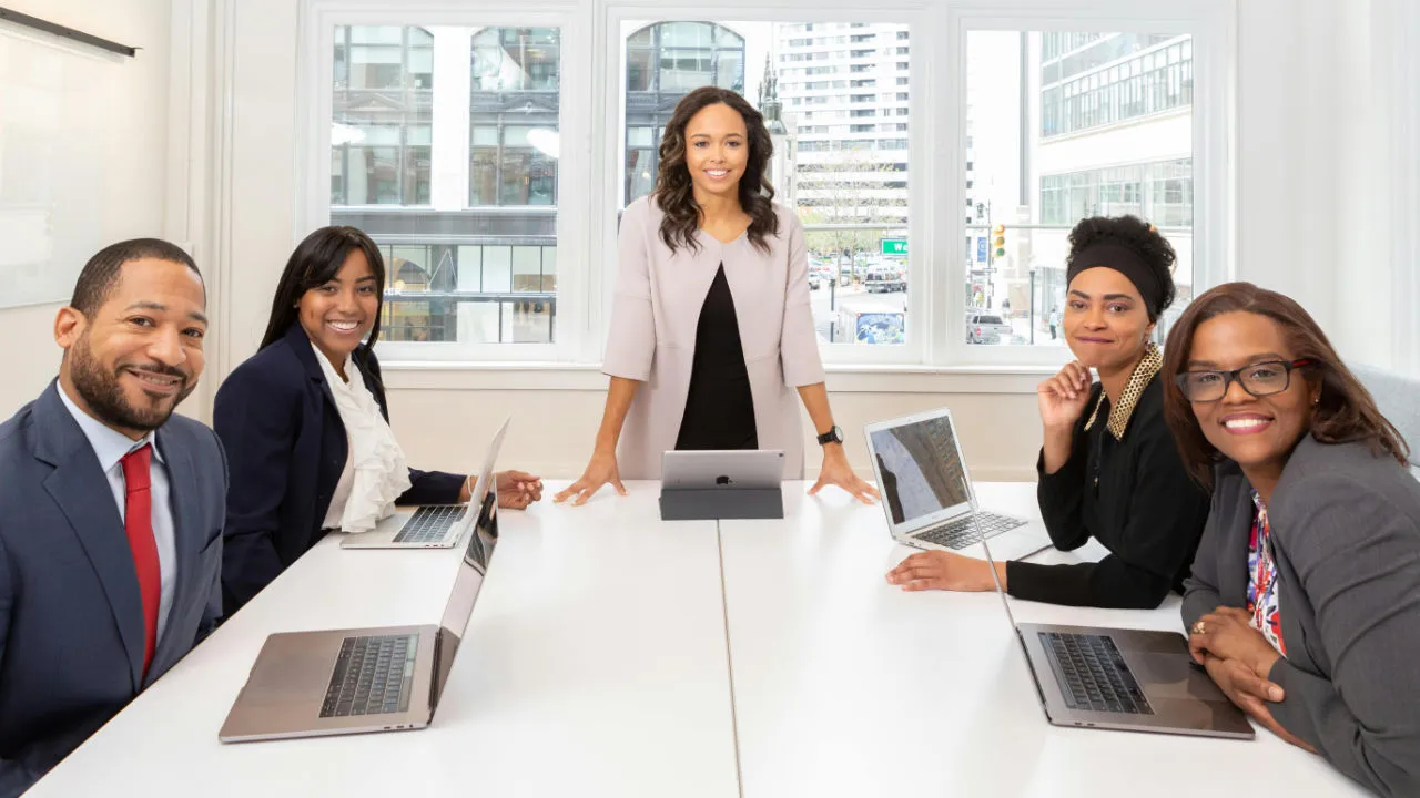 Smiling business team meeting in a modern office, representing successful E-2 visa approval.