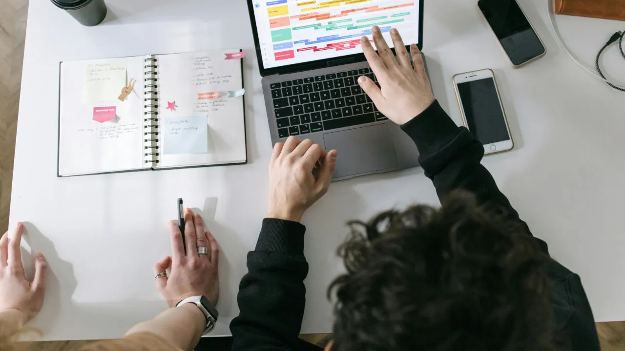 People planning business tasks on a laptop and notebook for E-2 visa work compliance.