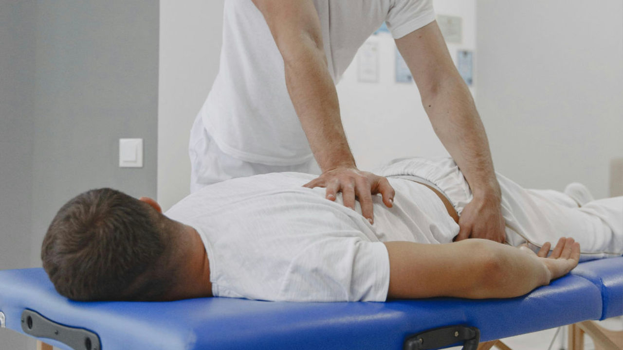 hysiotherapist giving treatment to a patient on a table, representing a business expansion under the L-1A visa.