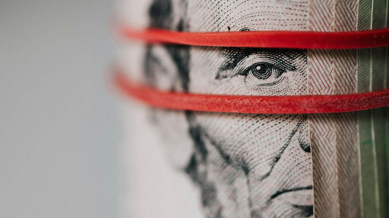 A close-up of a roll of U.S. currency held by a rubber band, symbolizing the E-2 visa investment funds.