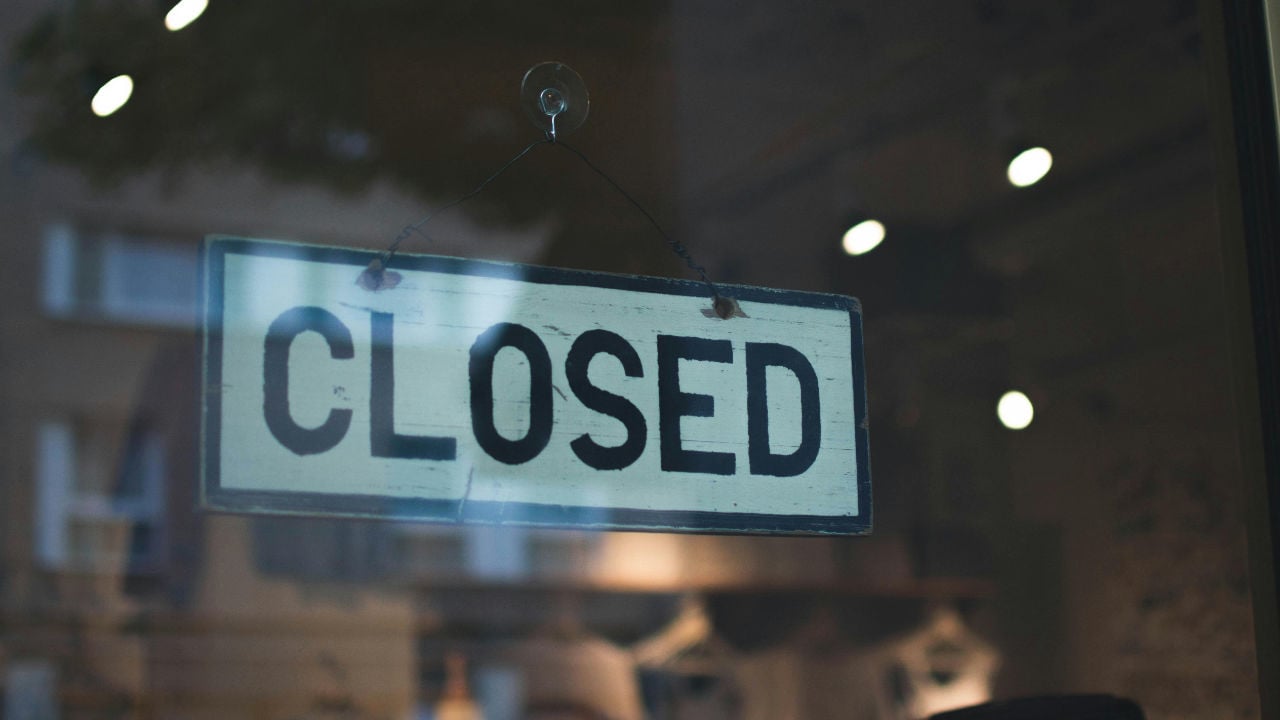 A "Closed" sign hanging on a glass door, representing what happens to an E-2 visa if the business fails.