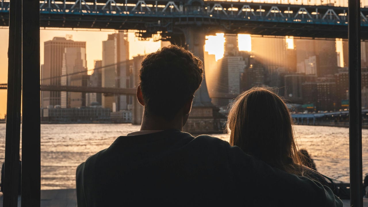A couple looking at a city skyline at sunset, contemplating the path from an E-2 visa to a green card for a spouse.