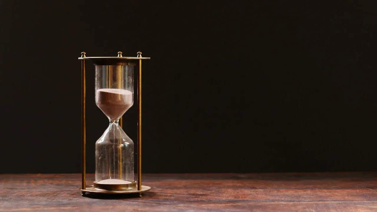 An hourglass on a wooden table, symbolizing the expiration of an E-2 visa and the importance of the I-94.