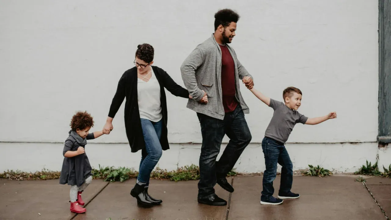 A family holding hands and walking together, representing the E-2 visa application process for families.
