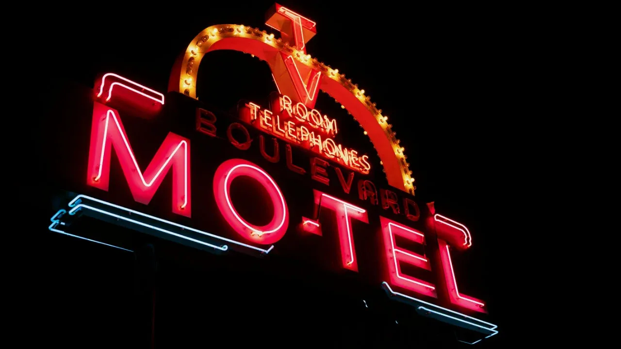 A bright red and blue neon sign for the "Boulevard Motel" glowing against a black night sky.