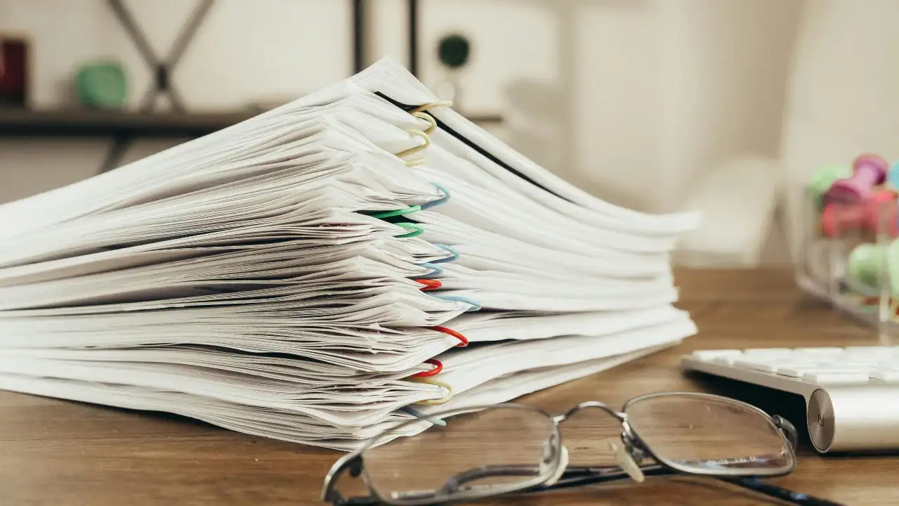 A stack of documents and a pair of glasses on a desk, representing the detailed requirements of the EB-5 Green Card program.
