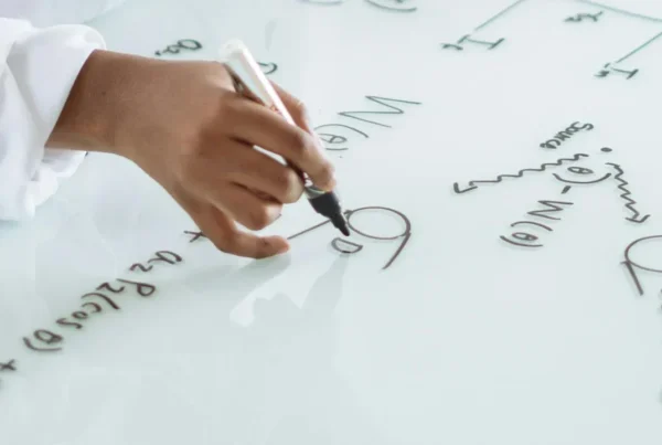 A person writing complex formulas on a whiteboard, representing the strategic planning needed for an O-1 visa.