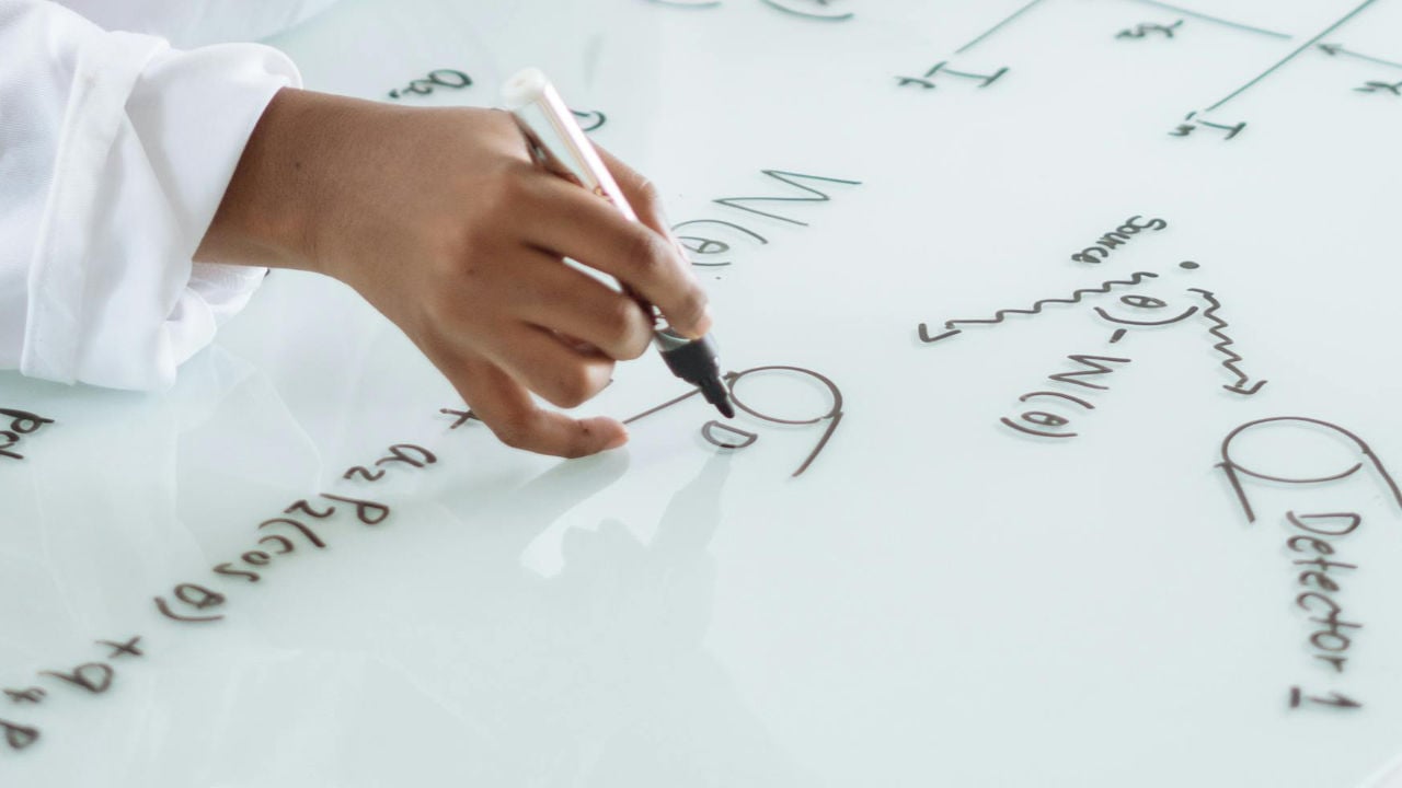 A person writing complex formulas on a whiteboard, representing the strategic planning needed for an O-1 visa.