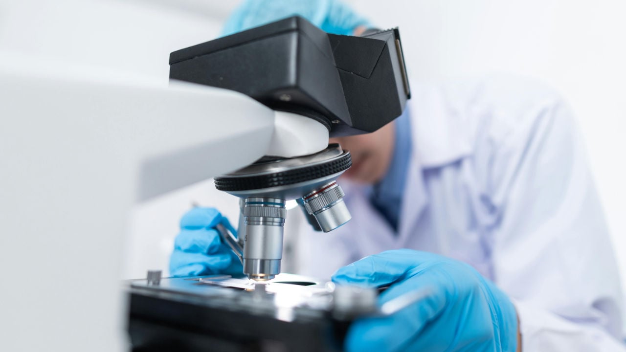 A scientist looking through a microscope, representing the high level of scrutiny and detail required for an EB-1A petition.
