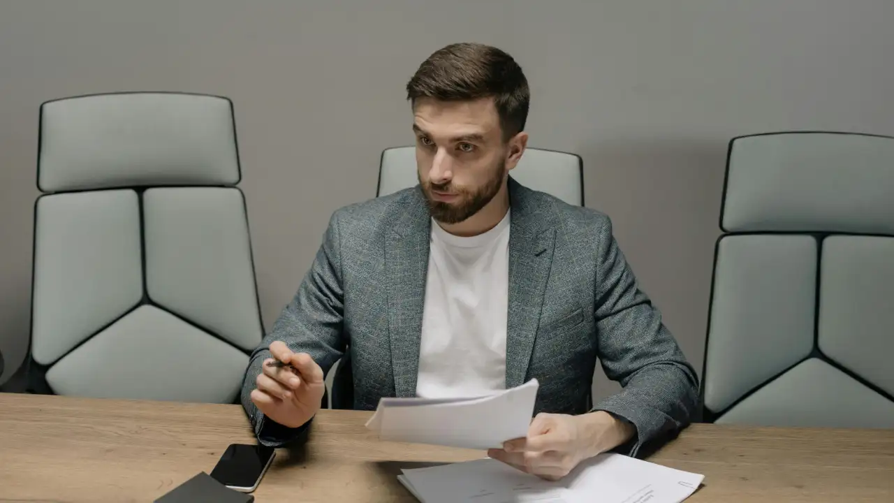 A businessman at a desk reviewing documents, considering the tax implications of an E-2 visa S corporation.