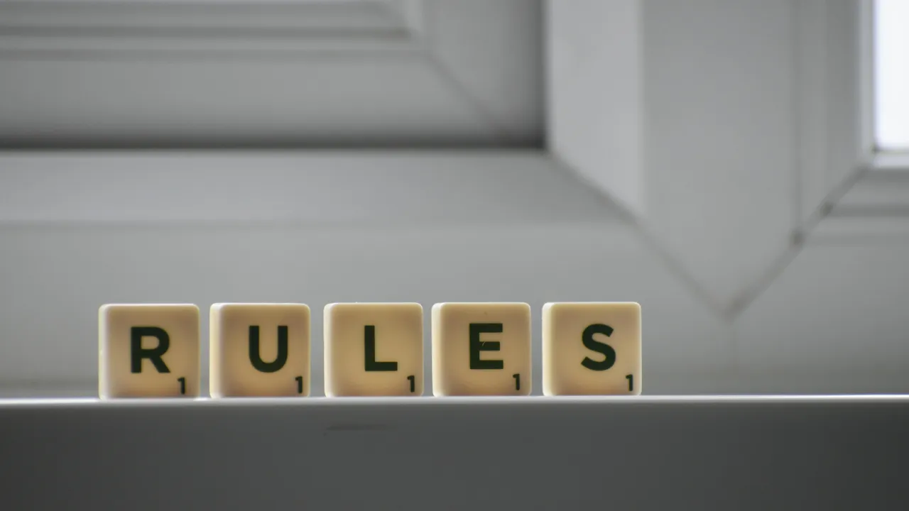 The word "RULES" spelled out in letter tiles, representing the E-2 visa requirements.