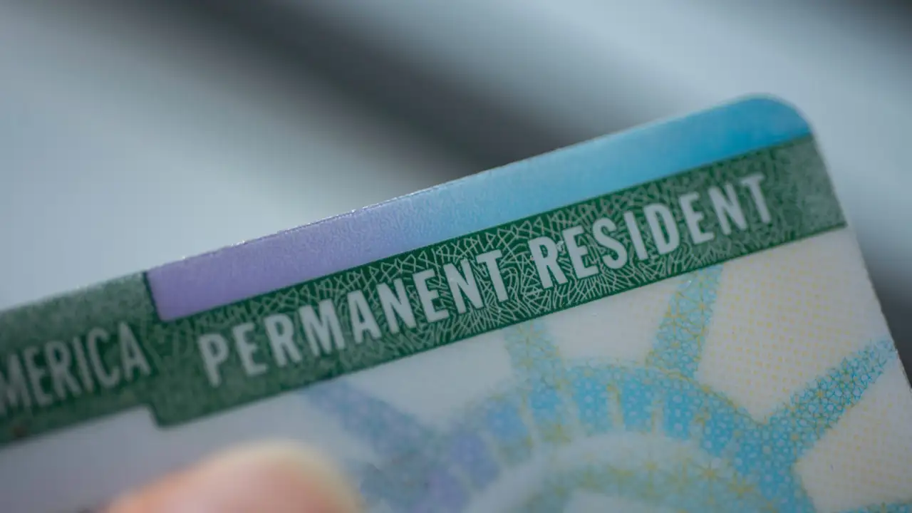 A close-up view of a U.S. permanent resident card, showing the text "PERMANENT RESIDENT."
