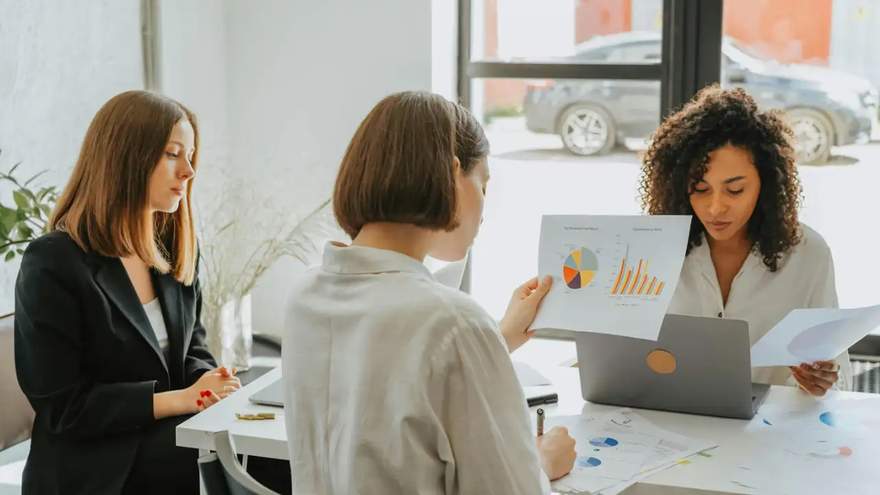 A team of business professionals in a meeting, reviewing charts and data, symbolizing the strategic planning needed for an E-2 visa renewal.