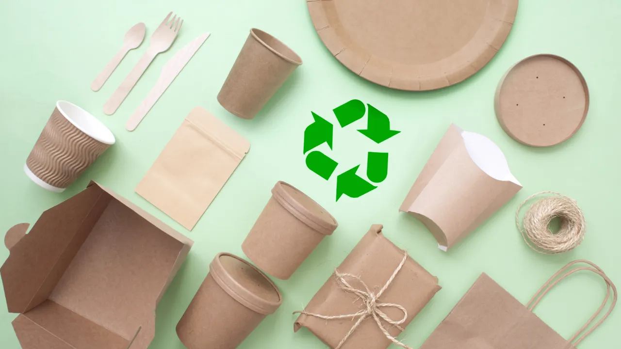 A flat lay image showing various biodegradable brown paper packaging items, like cups, containers, boxes, and wooden utensils, with a green recycling symbol in the center on a light green background.