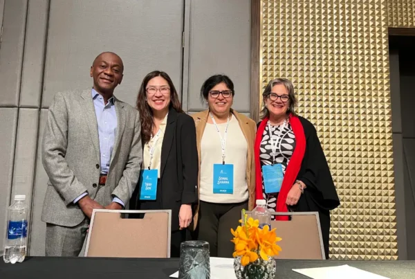 Four panelists, including Ian Scott, standing together at a conference table for a panel on E-2, H-1B, and L-1 visa trends.
