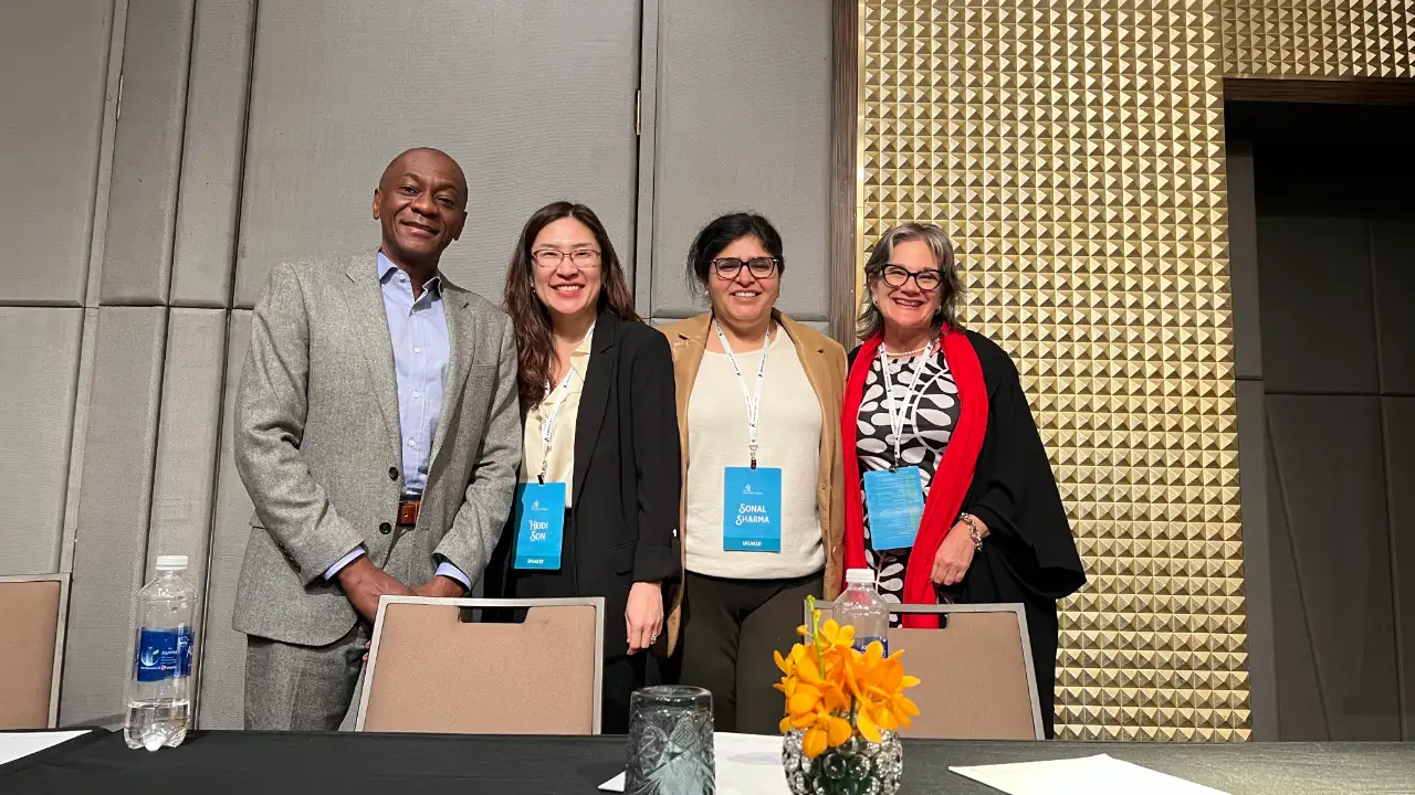 Four panelists, including Ian Scott, standing together at a conference table for a panel on E-2, H-1B, and L-1 visa trends.