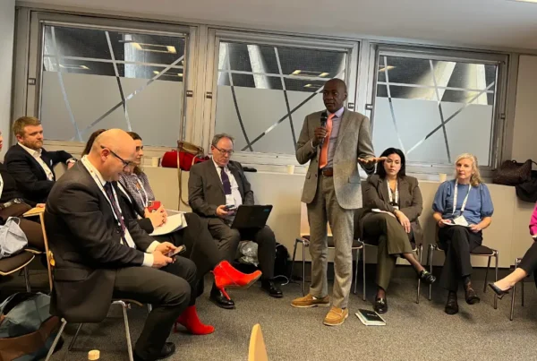 Speaker Ian Scott standing and addressing a panel of seated legal professionals at an international conference.