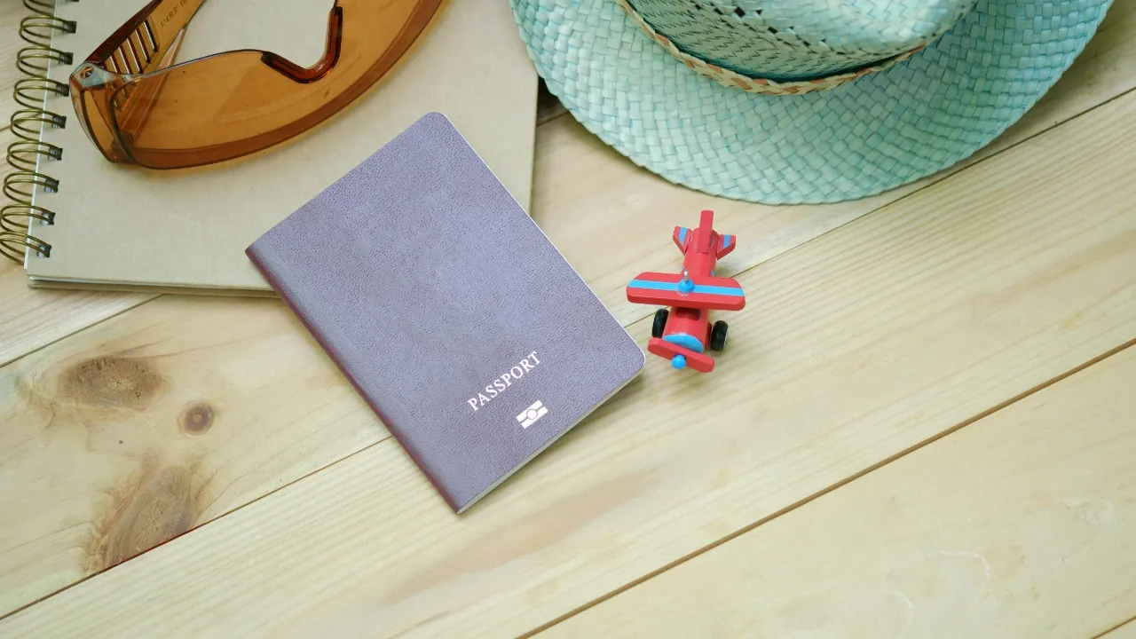A passport on a wooden desk with a notebook and travel items, representing planning for a USCIS extension.