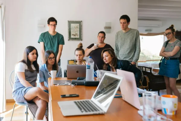 A diverse group of young professionals brainstorming around a laptop, representing a startup team working on innovation.
