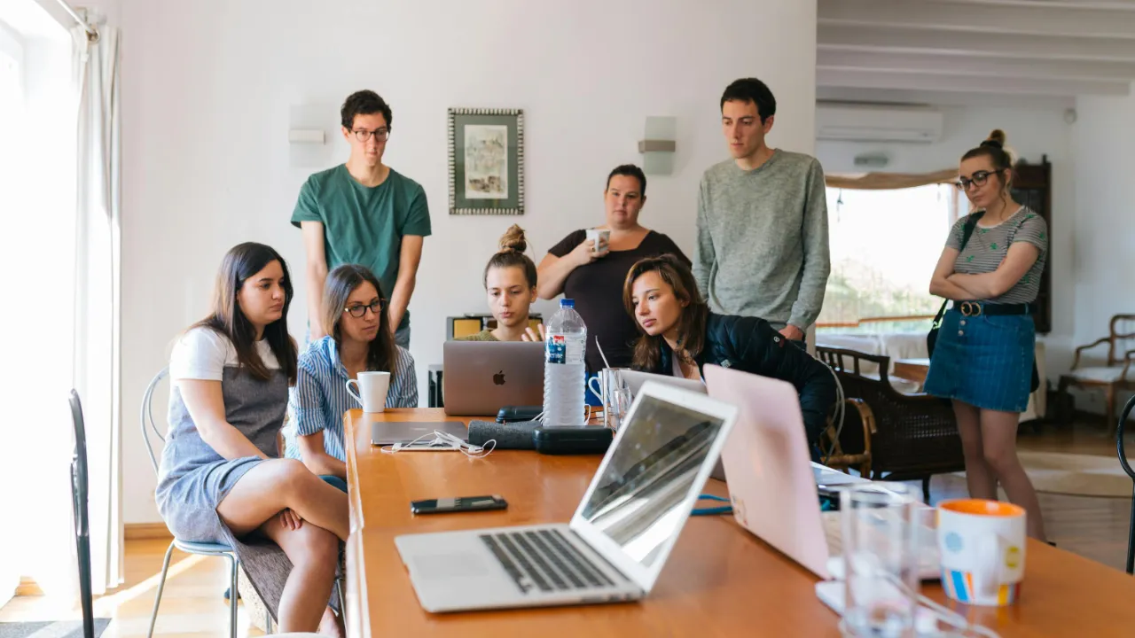 A diverse group of young professionals brainstorming around a laptop, representing a startup team working on innovation.