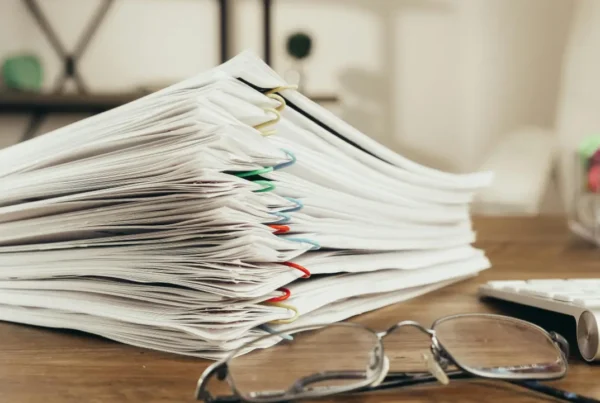 Stack of organised documents with colourful clips on a desk, representing E-2 visa due diligence process.