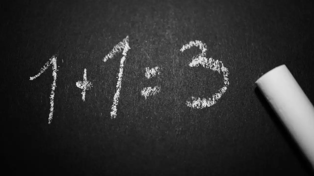 Chalkboard showing incorrect equation “1 + 1 = 3” written in white chalk.