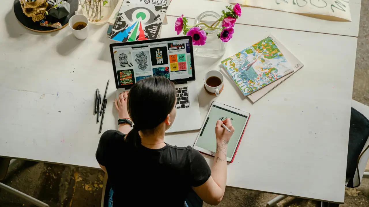 Professional working at a desk with laptop and tablet, representing job duties and professional roles for TN visa applicants