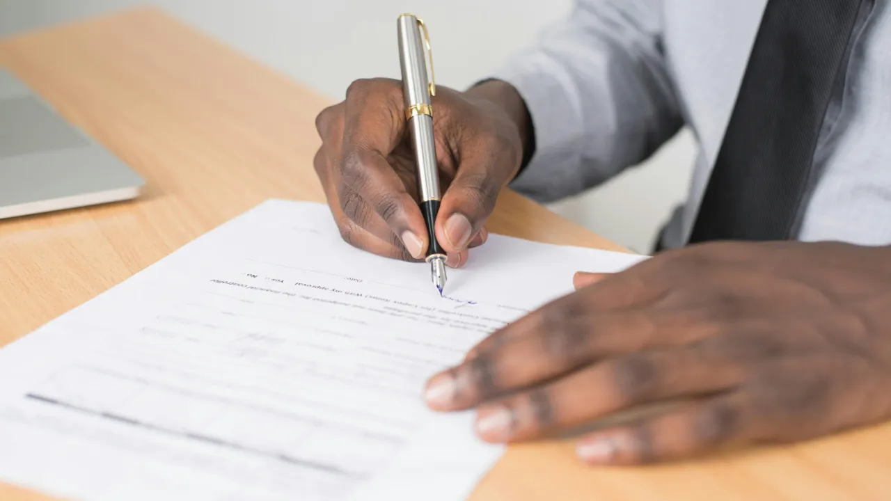 A close-up of a professional signing a document with a fountain pen, representing an expedite employment authorization request.