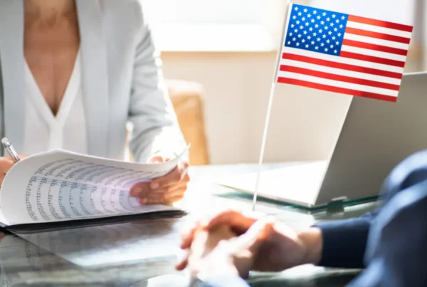 Person reviewing immigration documents at a desk with a U.S. flag during USCIS adjudicative hold processing.