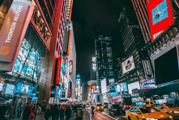 A vibrant night scene of Times Square in New York City with bright billboards, yellow taxis, and busy pedestrians.