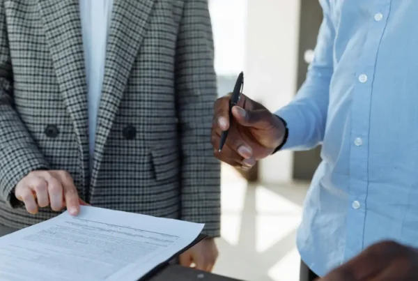 Two business professionals in professional attire reviewing and signing a legal contract for a corporate partnership.