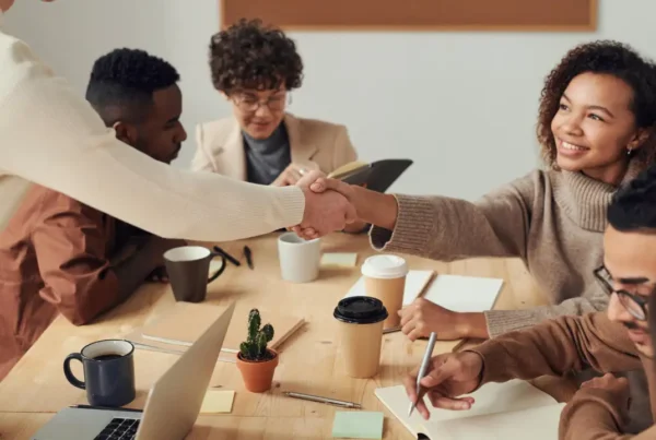 A professional group of diverse colleagues shaking hands in a bright, modern office to symbolize a successful employee transfer.
