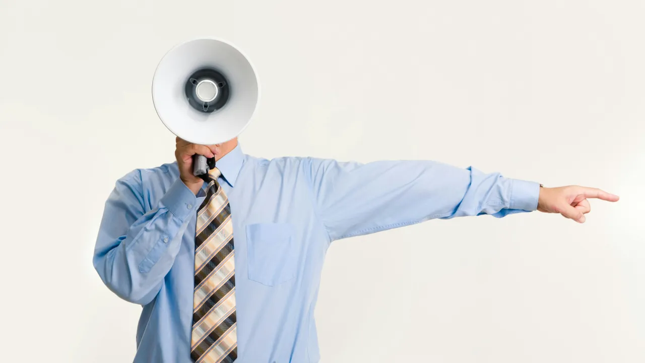 A professional in a blue shirt and tie holding a megaphone and pointing, symbolizing leadership, authority, and the direction of a business enterprise.