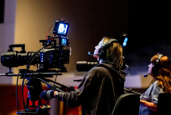 Two camera operators filming with professional video equipment in a studio setting.