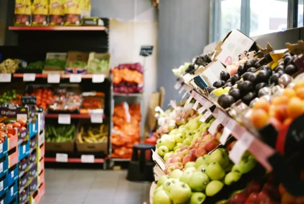 Shelves of fresh fruits and vegetables arranged inside a small grocery store.
