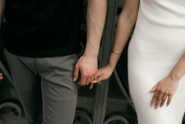 A close-up of a couple holding hands in front of a house, representing the security and stability that valid work authorization provides for families.