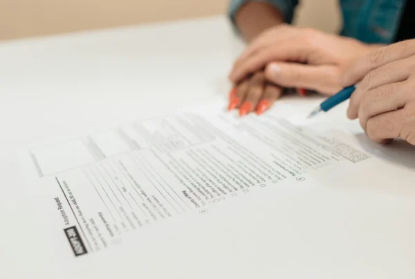 Two people reviewing and signing an official document on a white desk.
